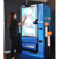 A woman using a vending machine with a thick glass touch screen