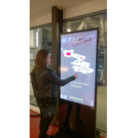 A woman using a PCAP touch screen totem