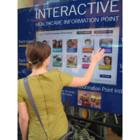 A woman using a through-window self service touch screen kiosk