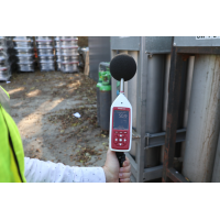 Environmental noise decibel meter being used for industrial noise assessment.