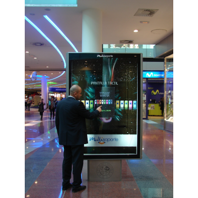 Un hombre que usa una pantalla táctil capacitiva proyectada en un centro comercial.