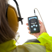 Un trabajador industrial que usa un medidor de vibraciones de mano y brazo de Pulsar Instruments.