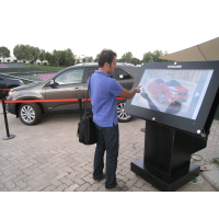 Un homme utilisant un kiosque extérieur avec un écran tactile en verre épais