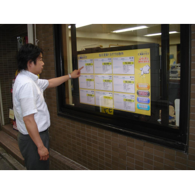 Mężczyzna używający 40-calowego ekranu dotykowego nakładanego na okno sklepu